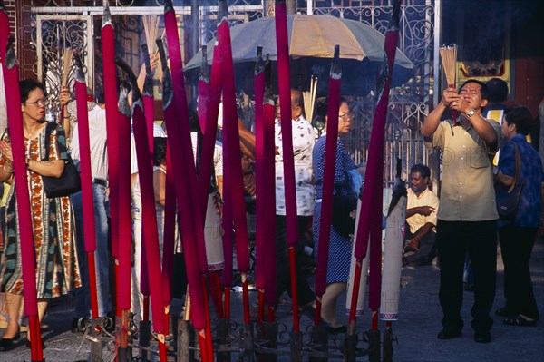 MALAYSIA, Penang, Georgetown, "Goddess of Mercy Temple, also known as Kuan Yin Teng.  Exterior with worshippers and large, pink, burning incense sticks."