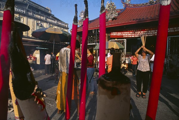 MALAYSIA, Penang, Georgetown, "Goddess of Mercy Temple, also known as Kuan Yin Teng.  Exterior with worshippers and large, pink, burning incense sticks."