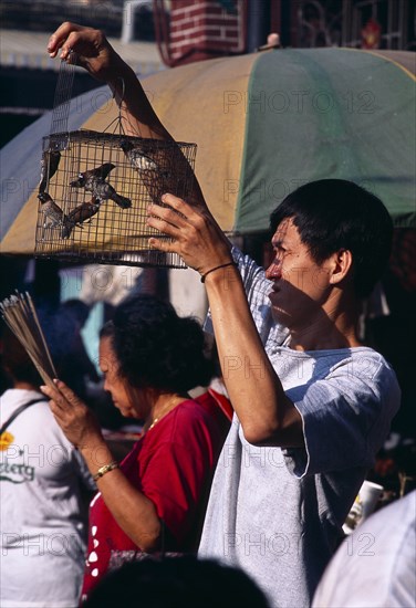 MALAYSIA, Penang, Georgetown, "Goddess of Mercy Temple, also known as Kuan Yin Teng.  Man releasing caged birds to attain merit for the afterlife."