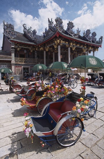 MALAYSIA, Penang, Georgetown, "Koo Kongsi, the Dragon Mountain Hall. Exterior of clan house with line of decorated bicycle rickshaws in the foreground."