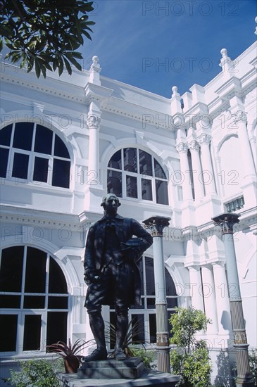 MALAYSIA, Penang, Georgetown, Penang Museum and Art Gallery.  Part view of white painted exterior with statue of Francis Light in the foreground.