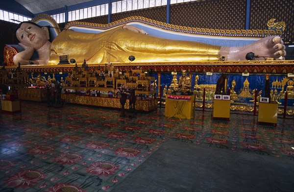 MALAYSIA, Penang, Georgetown, Wat Chayamangkalaram.  Interior with 32 metre long reclining Buddha lying behind display of various smaller figures and statues.
