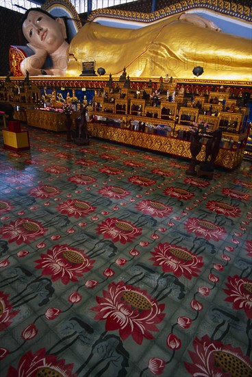 MALAYSIA, Penang, Georgetown, Wat Chayamangkalaram.  Interior with 32 metre long reclining Buddha lying behind display of various smaller figures and statues.