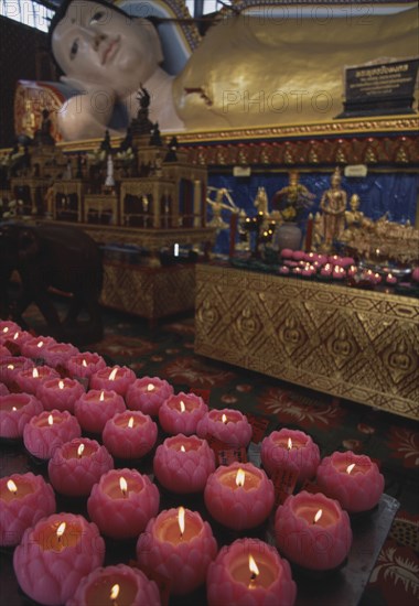 MALAYSIA, Penang, Georgetown, Wat Chayamangkalaram. Interior. Part view of reclining Buddha with pink lighted candles in the shape of lotus flowers in the foreground.
