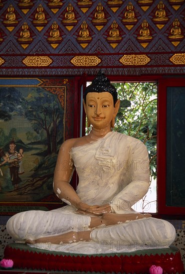 MALAYSIA, Penang, Georgetown, Wat Chayamangkalaram.  Interior with seated Buddha figure in meditative pose framed by red window frame.  Wall painting depicting religious scene at side.