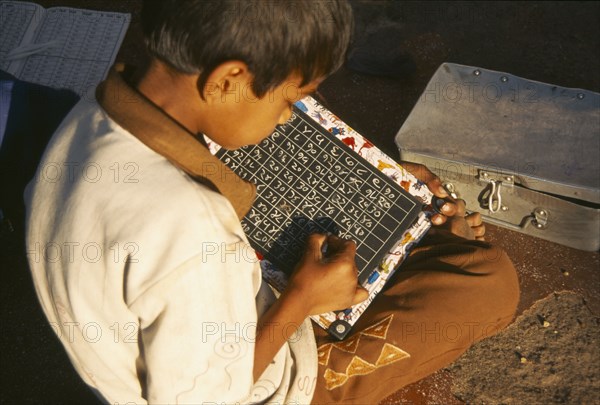 INDIA, Maharashtra, Nasik, School boy using chalk and slate