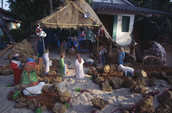 INDIA, Goa, Palolem, Young girl looking at Christmas nativity scene on sand.