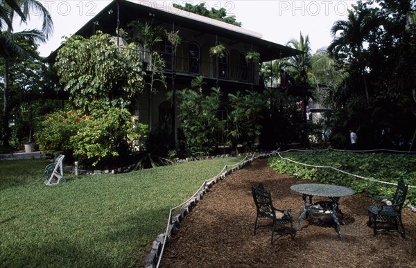 USA, Florida, Key West , "Hemmingway’s home, exterior and garden with iron table and cats asleep on chairs in the foreground"