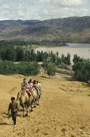 CHINA, Ningxia, Yellow River, People on traveling up hill on camels
