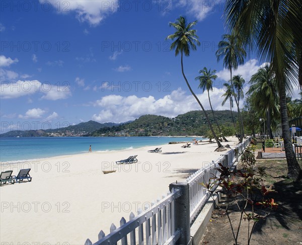 WEST INDIES, Grenada, Grand Anse Beach, View along empty sandy beach towards turquoise sea and hills seen from across water