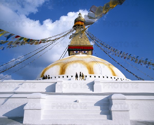 NEPAL, Kathmandu, Bodnath Stupa.  White painted steps leading to dome of stupa painted with eyes and hung with prayer flags.