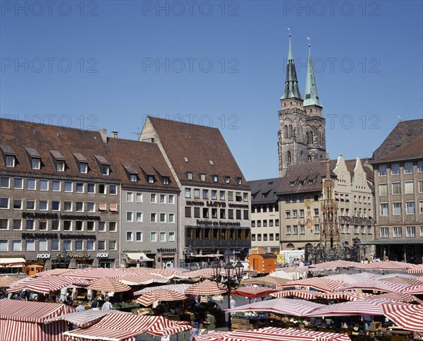 GERMANY, Bavaria, Nuremberg, The Hauptmarkt. Market stalls with red and white striped canopies in the square beneath the twin spired church