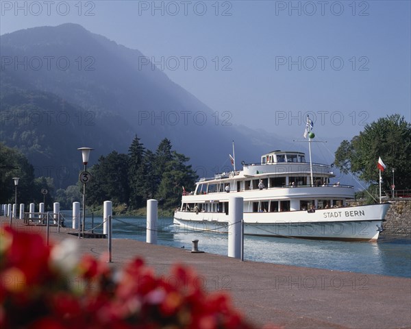SWITZERLAND, Bern Oberland, Interlaken, White passenger ferry nearing quay with misty wooded mountains in the distance