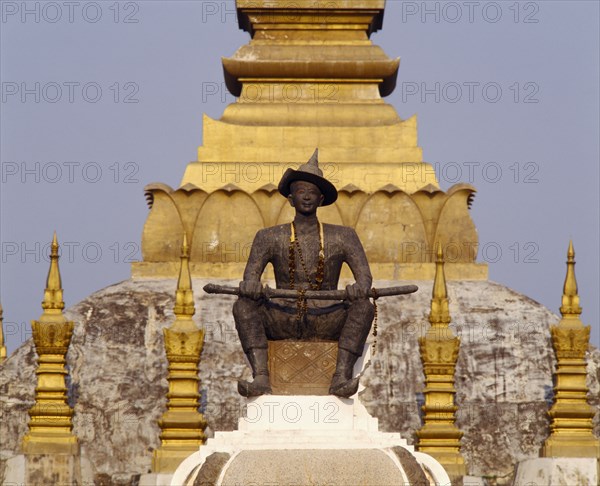 LAOS, Vientiane, Pha That Luang Sacred Stupa with statue of King Setthathirat in foreground.