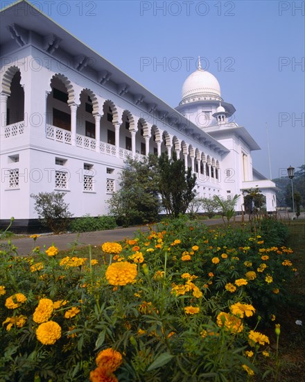BANGLADESH, Dhaka, Supreme Court Building exterior facade with ornate white arches and orange flowers in foreground.