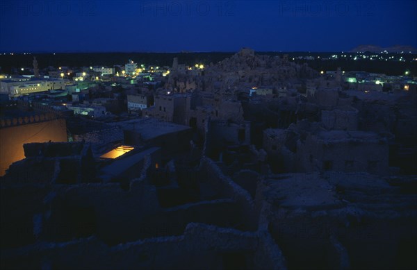 EGYPT, Western Desert, Siwa Oasis, View across town towards Shali Fortress at night with oasis in the background