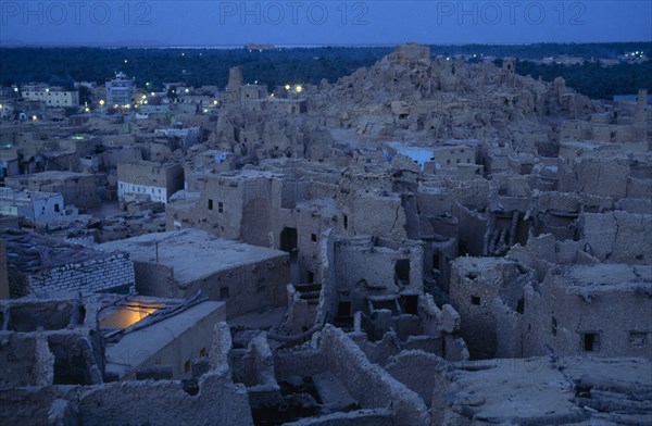 EGYPT, Western Desert, Siwa Oasis, View across town towards Shali Fortress at night with oasis in the background