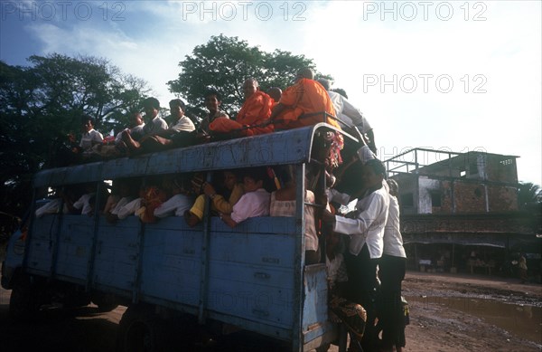 CAMBODIA, Kompong Chhnang, "Crowded public bus, passengers sitting on roof and holding on to back as well as packed inside."
