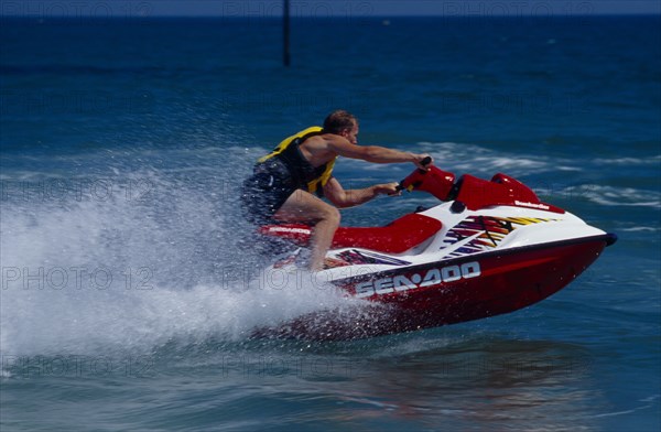 20002911 SPORT Watersports Jet Ski Man riding a jet ski on the sea at Littlehampton in West Sussex  England.  Viewed from the side.