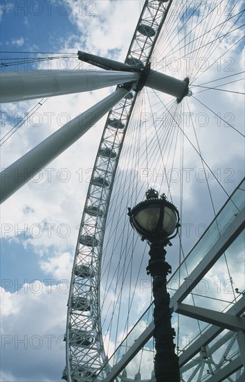 ENGLAND, London, British Airways London Eye Milennium wheel view through the spokes of the ride with cloudy sky .