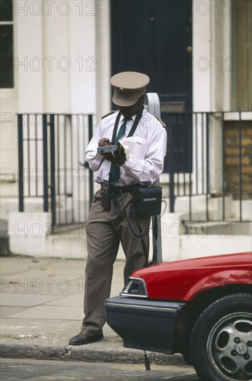 ENGLAND, London, Illegally parked car being giver parking ticket by traffic warden