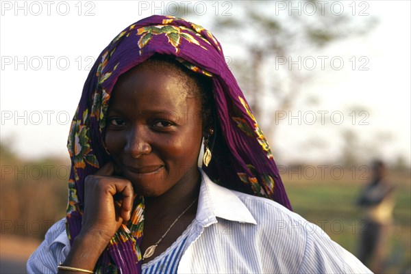 BURKINA FASO, Bobo Dioulassou, "Portrait of a smiling woman wearing a purple headscarf, working in Paddy field."