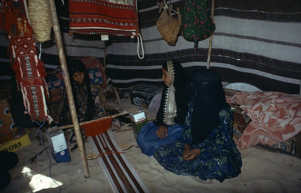 QATAR, People, Bedouin girls sitting inside tent decorated with hanging textiles weaving