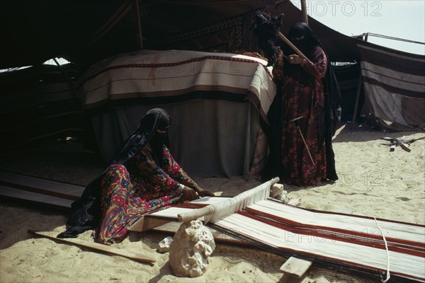 QATAR, Craft, Bedouin women weaving and spinning outside tent.