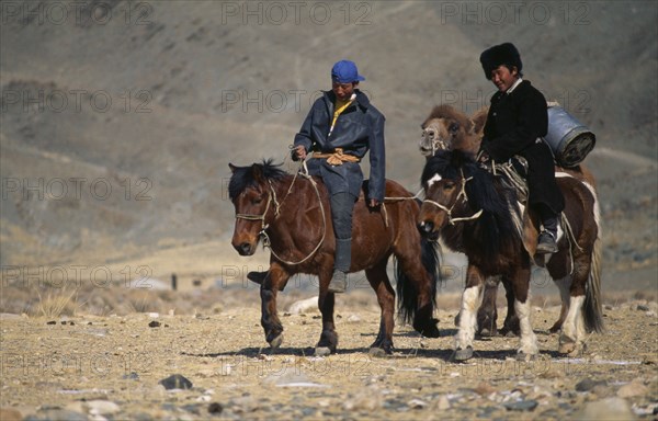 MONGOLIA, Bayan Olgii Province, Kazakh men on their way to the Kazakh New Year festivities riding horses and leading pack camel.