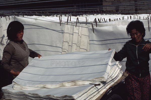 SOUTH KOREA, Crafts, Women stacking sheets of hand-made mulberry paper used for door and window screens