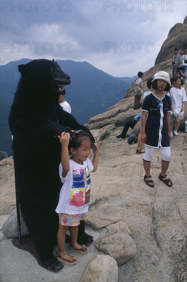 SOUTH KOREA, Soraksan Nat. Park, Sorak Mountains, "Tourists crowd onto Chipsonbong summit, child posing with stuffed bear."