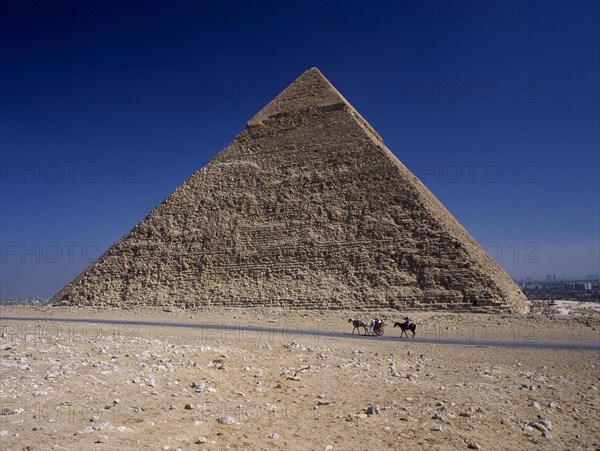 EGYPT, Cairo Area, Giza, Tourist horse and carriage passing by pyramid of Khufu.