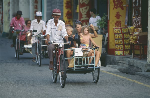 MALAYSIA, Melaka, Tourists on bicycle rickshaw in the Chinatown district of the former trading port of Melaka