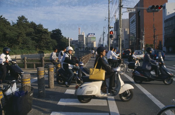 JAPAN, Shikoku, Matsuyama, Commuters on scooters and bicycles waiting to cross road.
