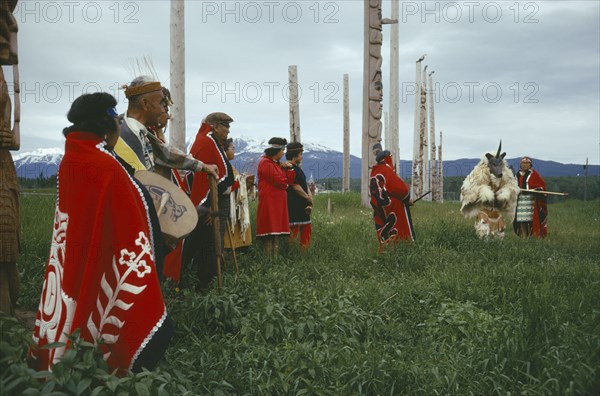 CANADA, British Columbia,  Kwakiutl, Native Indian Kwakiutl tribe totem poles with tribesmen and a dancer dressed as an animal deity