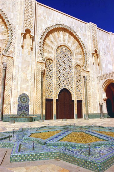 MOROCCO, Casablanca, Hassan II Mosque courtyard with mosaic star shaped brickwork fountain and archway beyond