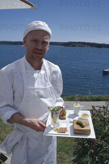 SWEDEN, Oaxen Island, Magnus Ech owner and chef holding a tray of food at Oaxen Skargards Krog restaurant