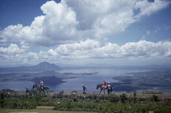 PHILIPPINES, Luzon Island, Taal Lake, Tourists being led on horses along shores of lake in volcanic crater.