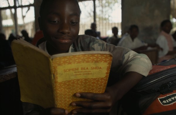 TANZANIA, Shinyanga, Mwenge Primary School child reading a text book in the classroom