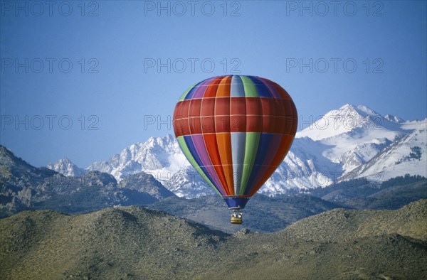 USA, California, Sierra Nevada, Hot Air Balloon rising against a backdrop of mountains
