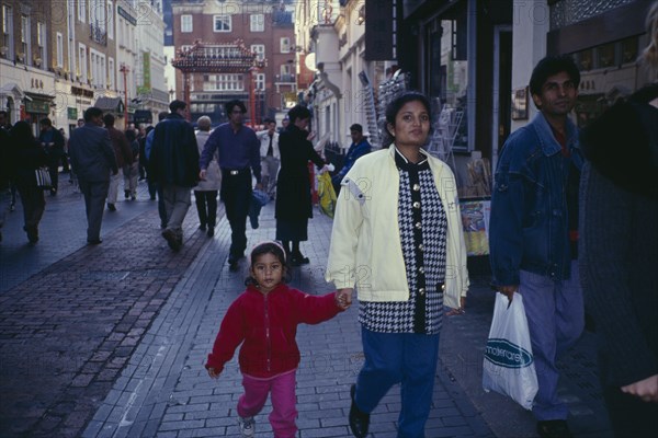 ENGLAND, London, Chinatown. Mixed crowd of shoppers with young family in foreground.