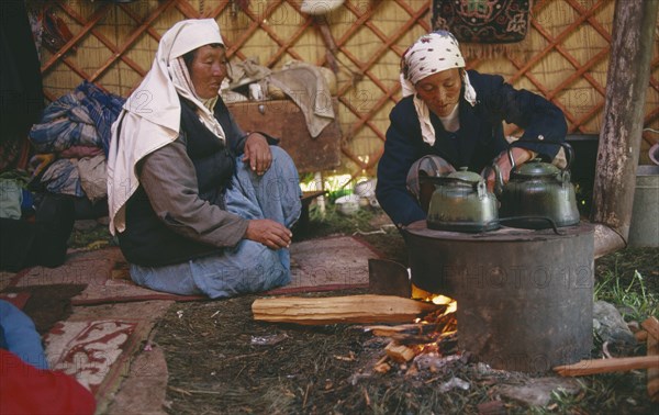 CHINA, Xinjiang Province, Kazakhs, Kazakh nomadic women brewing tea in their Kigizuy or felt tent in the Altay Mountains