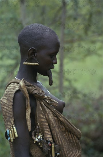 ETHIOPIA, Body Decoration, Mursi tribeswoman wearing multiple earrings in stretched earlobe with large hanging lip stretched by lip plate