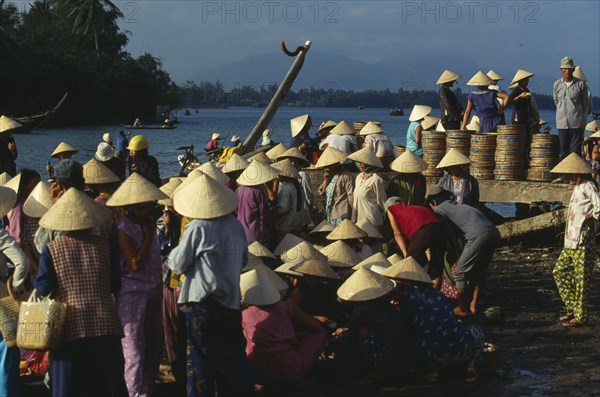 VIETNAM, Central, Hoi An, Women wearing traditional conical hats at the busy fish market beside the river