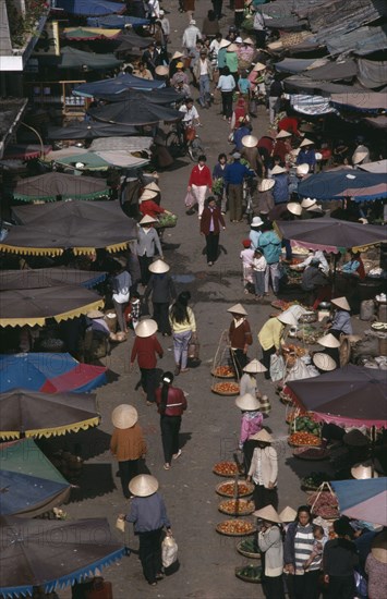 VIETNAM, South, Nha Trang, Market scene from above with people in conical hats walking amongst fruit and vegetable sellers with stalls under umbrellas along each side.