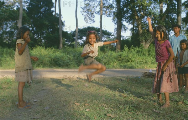 CAMBODIA, Angkor, Young girls with skipping rope playing beside road.