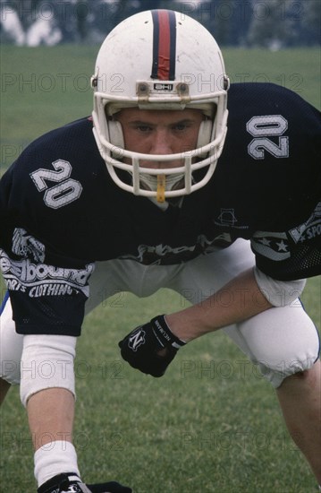 SPORT, Ball Games, American Football, British American footballer wearing body protector and helmet in defensive stance.