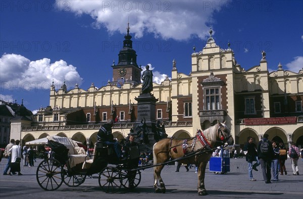 POLAND, Krakow, Horse drawn cart standing in the Market Square or Rynek Glowny with the facade of Drapers Hall behind