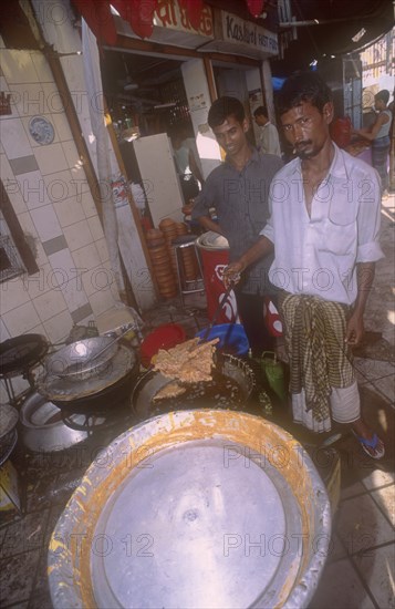 BANGLADESH, Dhaka, Street side shop preparing sweet  snacks for Iftar. The sunset breaking off the fast in the Islamic Ramadan.