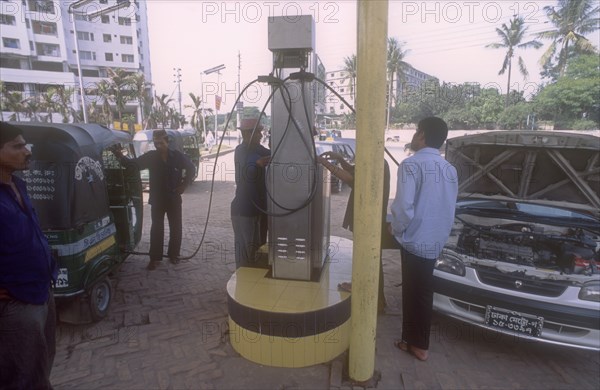 BANGLADESH, Dhaka, Men with car and LNG three wheeler taxi filling up on environmentally sound Liquid Natural Gas at one of  the few filling stations in Dhaka.